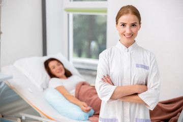 Smiling female doctor with arms crossed in hospital