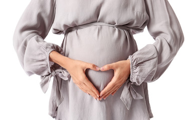 Young pregnant woman making heart with her hands against white background, closeup