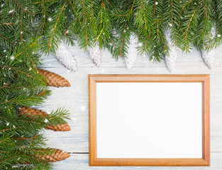 Fir tree branch with cones, frame, snowflake on white wooden background. Winter holidays concept