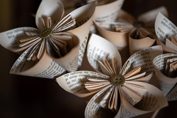 Fototapeta na wymiar Stylish origami-type hand-made folded paper flowers constructed from buttons and pages from an old book