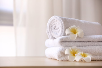 Fototapeta na wymiar Clean towels with flowers on table in room