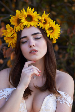  Portrait of a beautiful young girl with a wreath of sunflowers on her head. Autumn time.