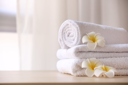 Clean towels with flowers on table in room
