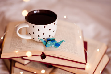 Mug of coffee with paper origami crane on open books close up. School time. Education concept.