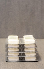 blisters with white gelatin capsules on a gray background with copy space