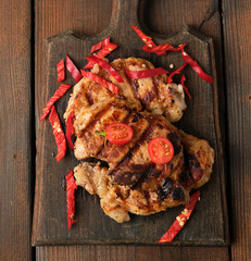 grilled pork pieces of meat on a grill lie on a vintage wooden board