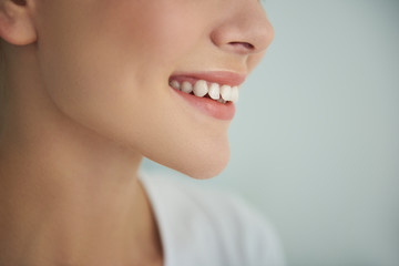 Young lady with perfect smooth skin smiling on light blue background