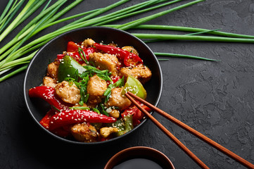 Schezwan Chicken or Dragon Chicken in black bowl at dark slate background. Szechuan Chicken is...