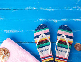 Naklejka premium pair of female beach slippers and a pink towel on a blue background
