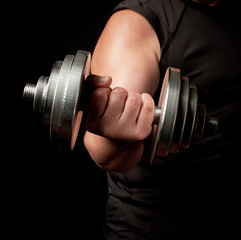 hand of a man with big biceps holds a steel type-setting dumbbell