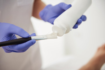 Aesthetician preparing gel for laser hair removal treatment