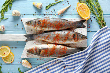 Board with fresh sea bass on wooden table