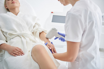 Young lady receiving laser hair removal treatment in modern beauty salon