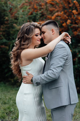 Fototapeta premium Portrait of beautiful young couple hugging among the branches of sea buckthorn. Happy family. Pretty woman and handsome man in love on nature. Sweethearts. Love story