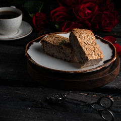 healthy bread with seeds on a white brown plate, on a dark wooden backdrop, cup of coffee and roses on background