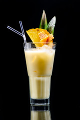 classic pina colada cocktail with reflection on dark background