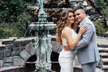 Young couple in love outdoor. Stunning sensual outdoor portrait of young stylish fashion couple posing in summer.  Handsome man and attractive young woman are in love.  Love is in the air