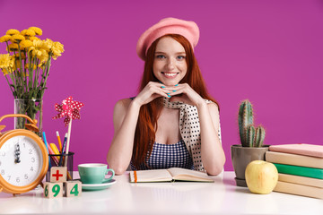 Image of gorgeous teenage girl studying with exercise books while sitting at desk