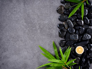 Scented candles and bamboo leaves on pebbles.