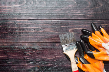 Paint brush, work gloves on painted wooden boards, top view