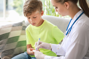 Doctor taking blood sample of diabetic boy at home