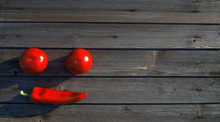 Smile with hot red pepper with two tomatoes on a dark wooden background