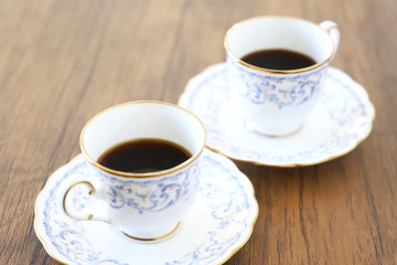 白い壁の背景に木製テーブル。その上に置かれたコーヒーカップ