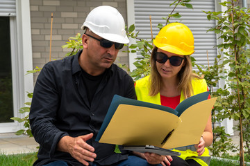 Male and female civil engineers sitting outdoors analyzing projects
