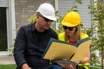 Male and female civil engineers sitting outdoors analyzing projects