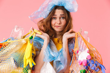 Photo of young confused woman holding bags with plastic waste