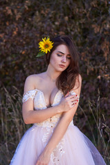 Beautiful cute sexy girl in a white dress  with deep neckline with a sunflower flower in her hair....