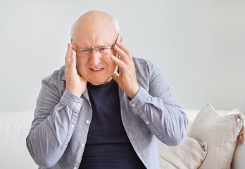 Senior man suffering from headache at home