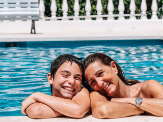 Fototapeta premium Mother and child are in the pool on a sunny summer day and pose affectionately for the camera.