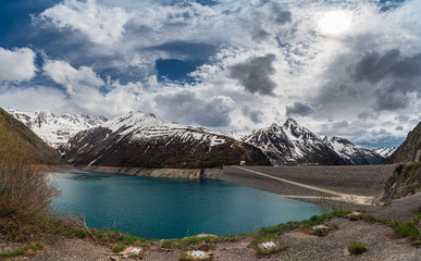 Obraz premium View of Lac de Grand Maison Lake in the French Alps with the Grand'Maison embankment dam on the right. The lake serves as the upper reservoir in a pumped-storage hydroelectric scheme