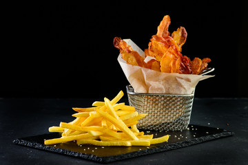 appetizer bacon chips and french fries on a dark background