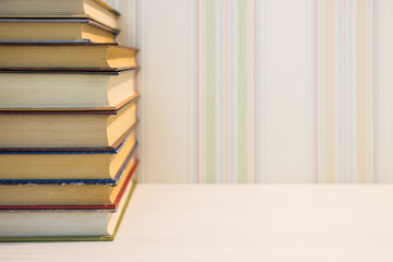 A neat stack of books on the edge of the white table