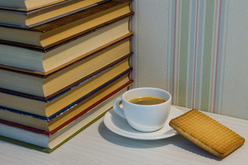 A stack of books and a Cup of espresso on a white table