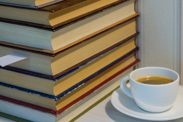 Fototapeta na wymiar A stack of books and a Cup of espresso on a white table