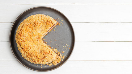Homemade cherry pie with crumbs on top on white wooden table. Top view. Copyspace.