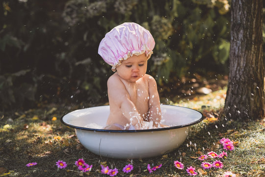 Baby kleines M&auml;dchen Kind sitzt in Emaillle Badewanne planschen im Garten rosa Badehaube lacht Sommer vintage