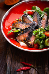 Fillet of beef smoked brisket with green salad on wooden table. Roasted Beef cooking idea