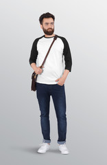 Bearded male model wearing white and grey 3/4 sleeve raglan shirt in dark blue denim jeans pant shoulder bag. isolated background