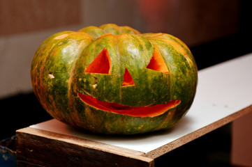 Halloween oblate pumpkin head. Orange pumpkin with a smile and eyes on wooden background.