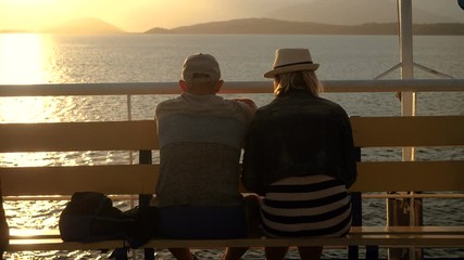 A man and woman in love looking at sunset from the deck of a cruise ship sailing the Mediterranean sea. Greece. 4K