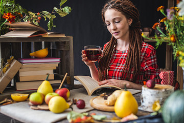 Woman reading a romantic book in a cozy warm atmosphere enjoying the autumn mood. Rustic table with yellow flowers