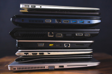 Stack of old laptops with dark background. Side