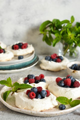 Classic dessert pavlova with cream and berries and almonds on the kitchen table. Portion dessert pavlova.