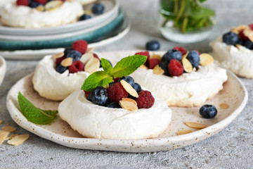 Classic dessert pavlova with cream and berries and almonds on the kitchen table. Portion dessert pavlova.