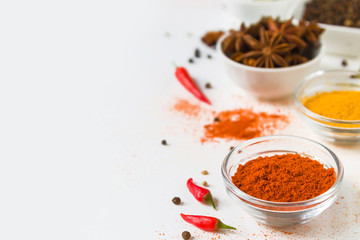 paprika in white bowl and colorful spices on a white background, with copy spice