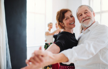 Senior couple attending dancing class in community center.